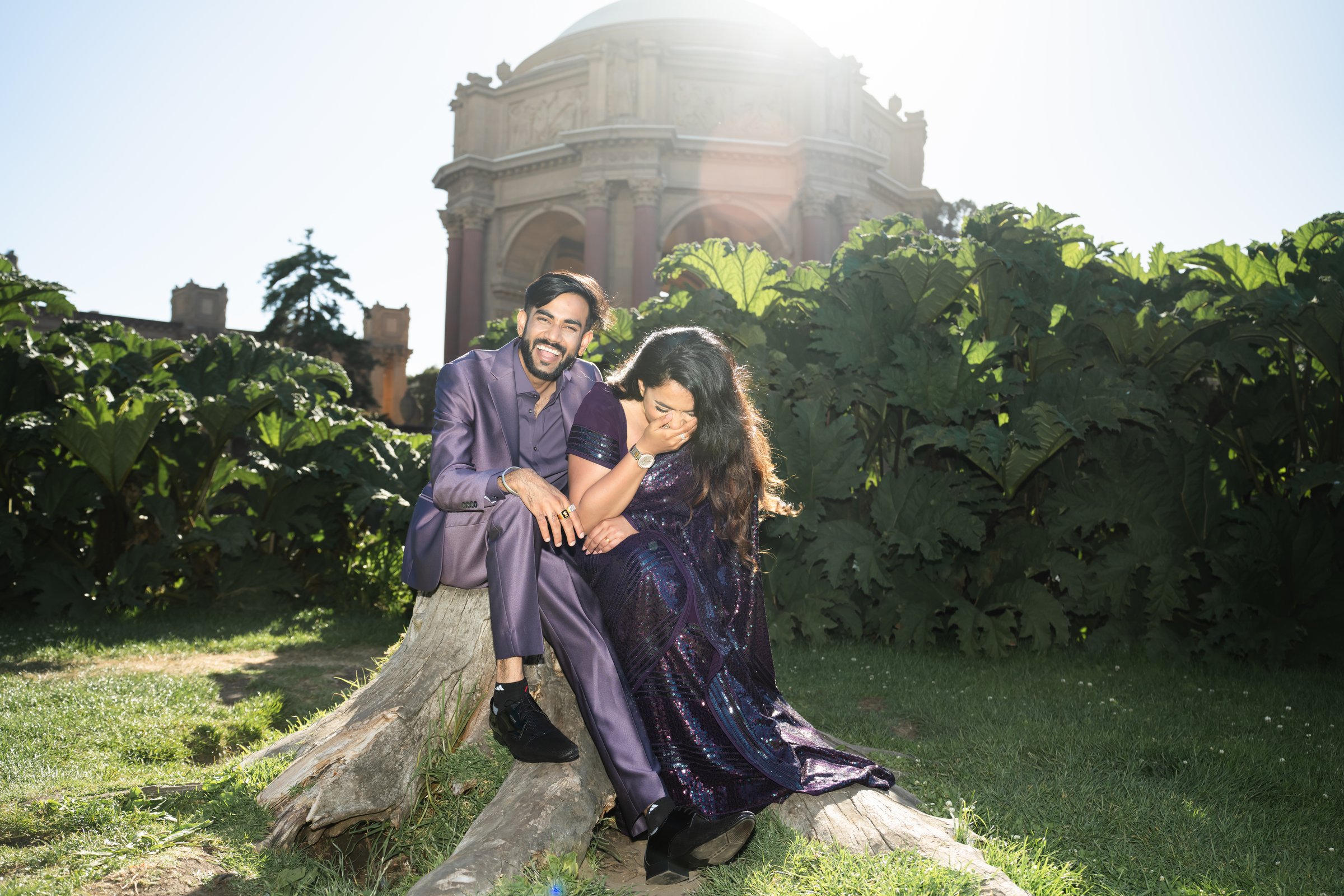 Triambika and varun's engagement shoot laughing on a log by the rotunda